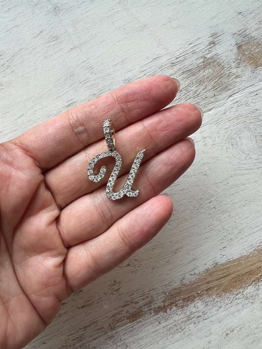 Dije letra "U" XL cursiva en oro y diamantes.
