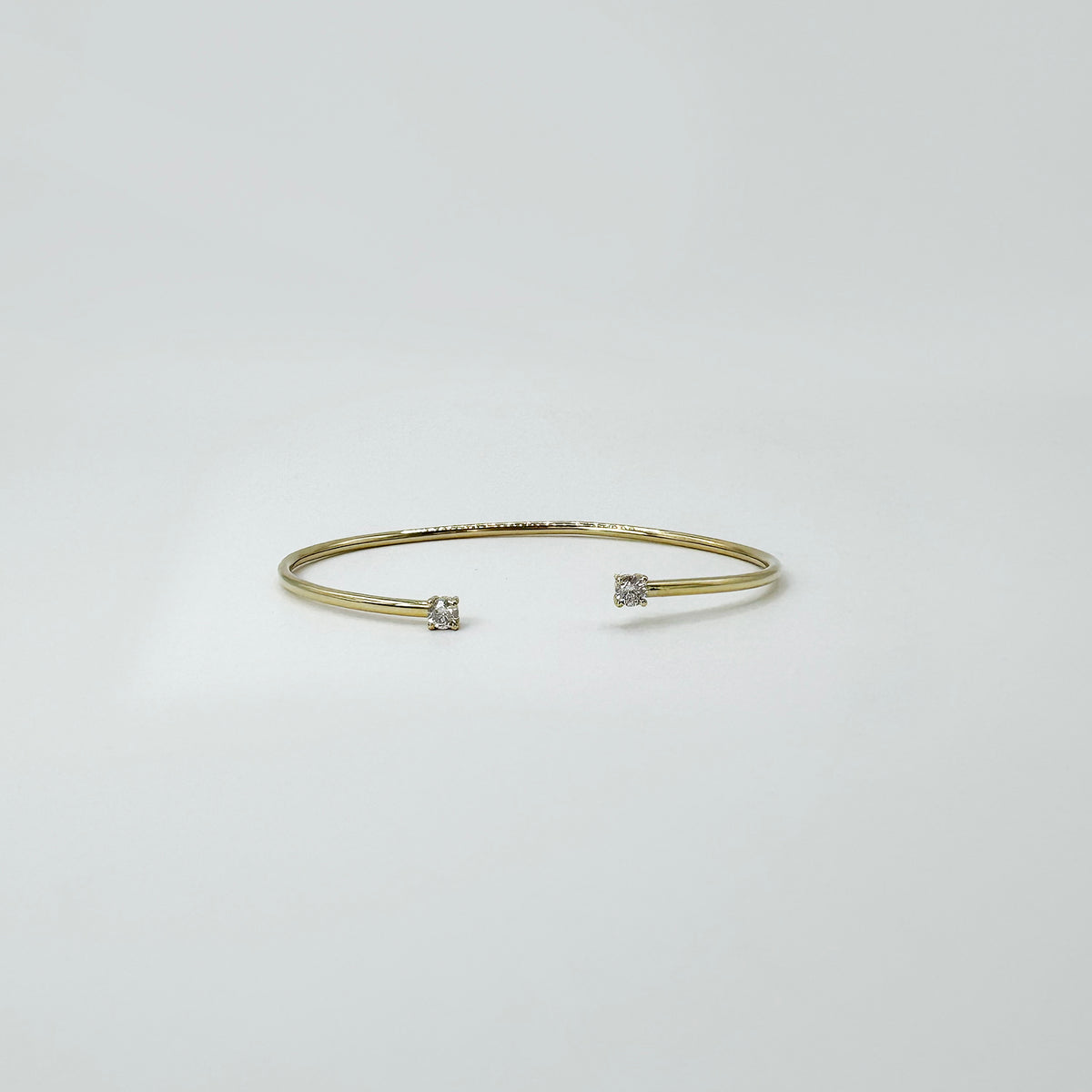 Pulsera rígida con dos diamantes naturales en oro amarillo.