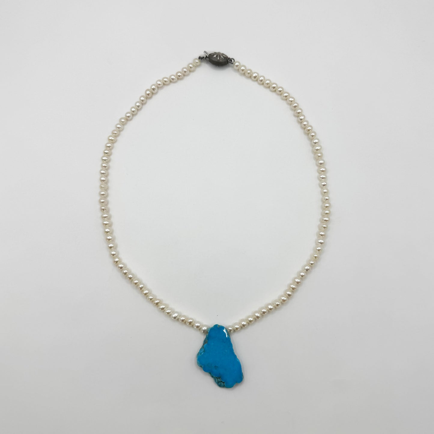 Collar de perlas con una turquesa.